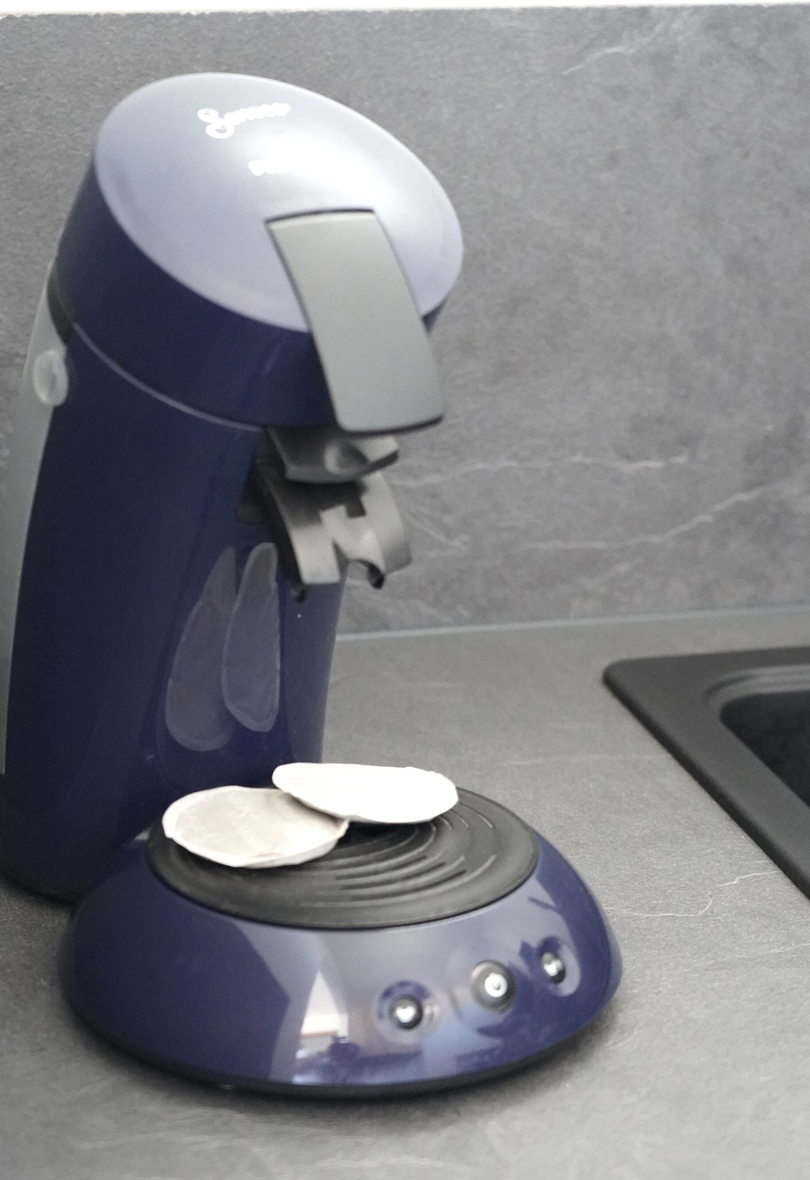Una cafetera azul con un solo portavasos sobre una encimera.