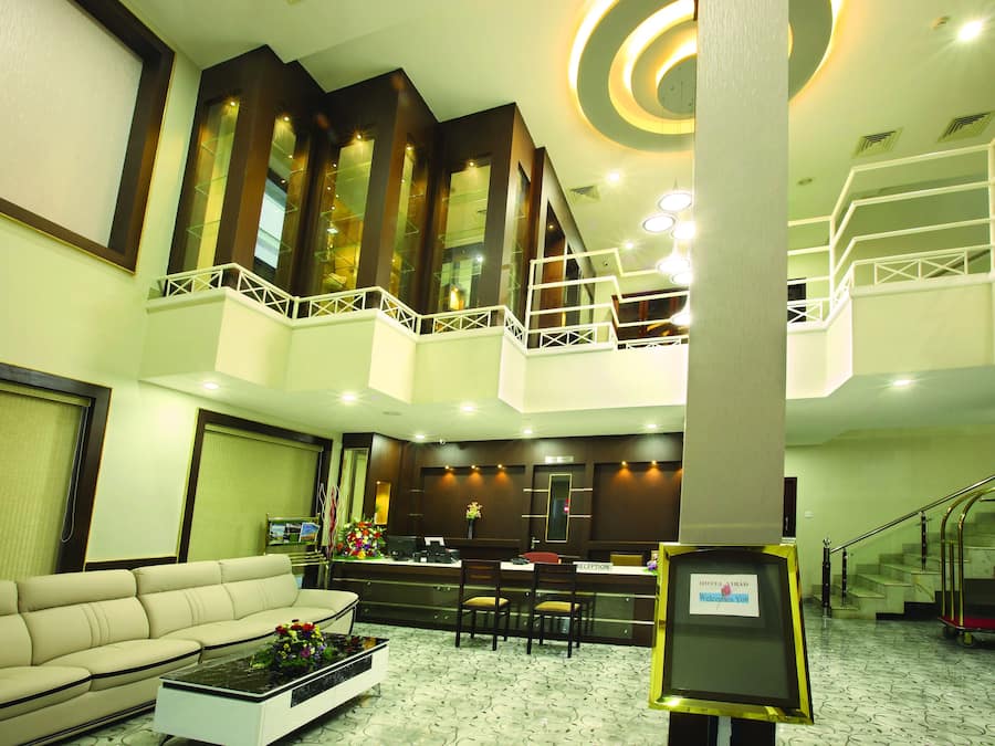 Un hall d’hôtel comprenant un comptoir d’accueil, un espace salon et un escalier menant à un étage supérieur.