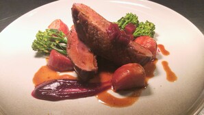 Une assiette de nourriture comprenant des tranches de viande, des légumes et de la sauce.