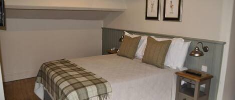 A bedroom with a bed, a nightstand, a lamp, and two framed pictures on the wall.