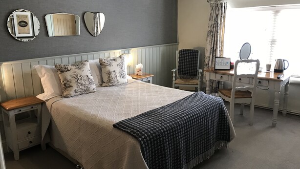 Une chambre à coucher bien rangée, avec un lit, des tables de chevet, un bureau et une chaise.