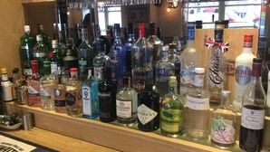Un bar où l’on trouve une grande variété de bouteilles d’alcool et de verres.