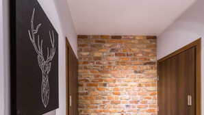 A hallway with a stone wall, a deer artwork on the wall, and a ceiling light fixture. - Dream Holiday-Apartamenty Chmielna Park (Gdansk)