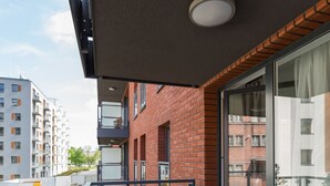 A balcony with a wooden floor, glass railings, and a view of neighboring buildings. - Dream Holiday-Apartamenty Chmielna Park (Gdansk)