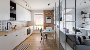 A modern kitchen with white cabinets, a wooden countertop, and a brick accent wall. - Dream Holiday-Apartamenty Chmielna Park (Gdansk)