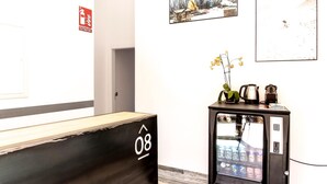 Un área de recepción con un mostrador de madera, una máquina expendedora y obras de arte en las paredes.