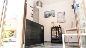 Zona de recepción de un hotel con un mostrador negro, una máquina expendedora y dos cuadros en la pared.