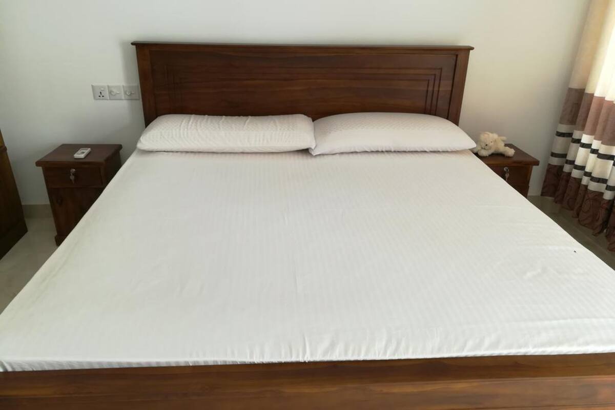 A neatly made bed with a wooden headboard, two pillows, and a bedside table with a lamp.