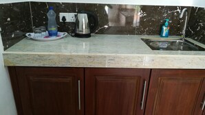 Una cocina con encimera de mármol, hervidor, botella de agua y dispensador de jabón.