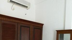 Una habitación con un armario de madera grande, un tocador de madera pequeño y un aire acondicionado instalado en la pared.