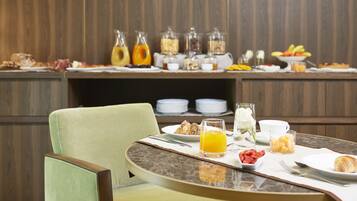 Un buffet de petit-déjeuner proposant divers aliments et boissons, une table à manger avec une chaise, et un mur en bois en arrière-plan.
