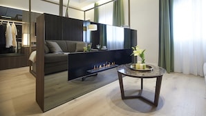 A modern living room with a sofa, a coffee table with candles, a fireplace, and a mirror reflecting the room. - Messori Suites (Florence)