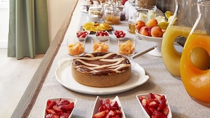 A breakfast buffet with various fruits, pastries, and a pitcher of orange juice. - Messori Suites (Florence)