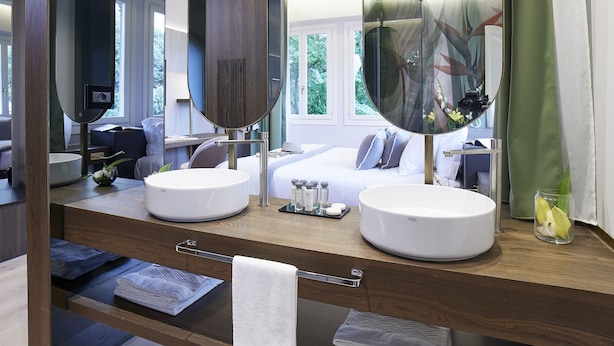 A modern bathroom with two sinks, a large mirror, and a wooden vanity. - Messori Suites (Florence)