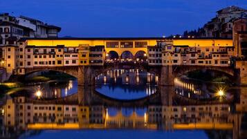 Un edificio storico con un arco centrale e un bacino d'acqua specchiante di fronte.