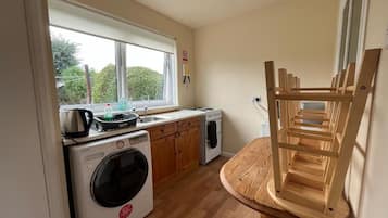 Cocina funcional con lavadora, estufa y ventana con vistas al verdor.
