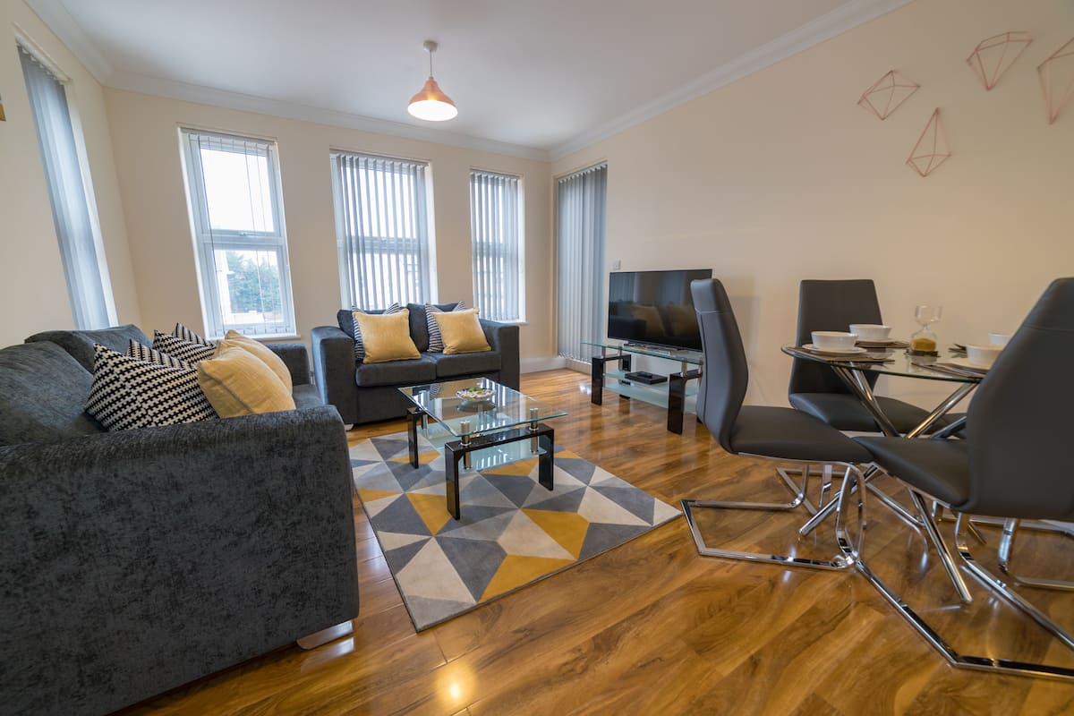 A modern living room with a sofa, armchairs, a coffee table, and a TV.