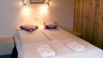 Un lit double recouvert d’une couvre-lit en dentelle blanche, avec deux oreillers et deux serviettes pliées.