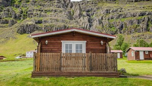 Una cabaña de madera con techo rojo, valla de madera y puerta blanca.