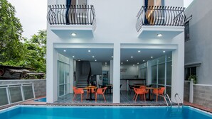 A modern two-story building with a swimming pool, outdoor seating area, and a balcony. - Silver Moon Villa Hoi An (Da Nang)