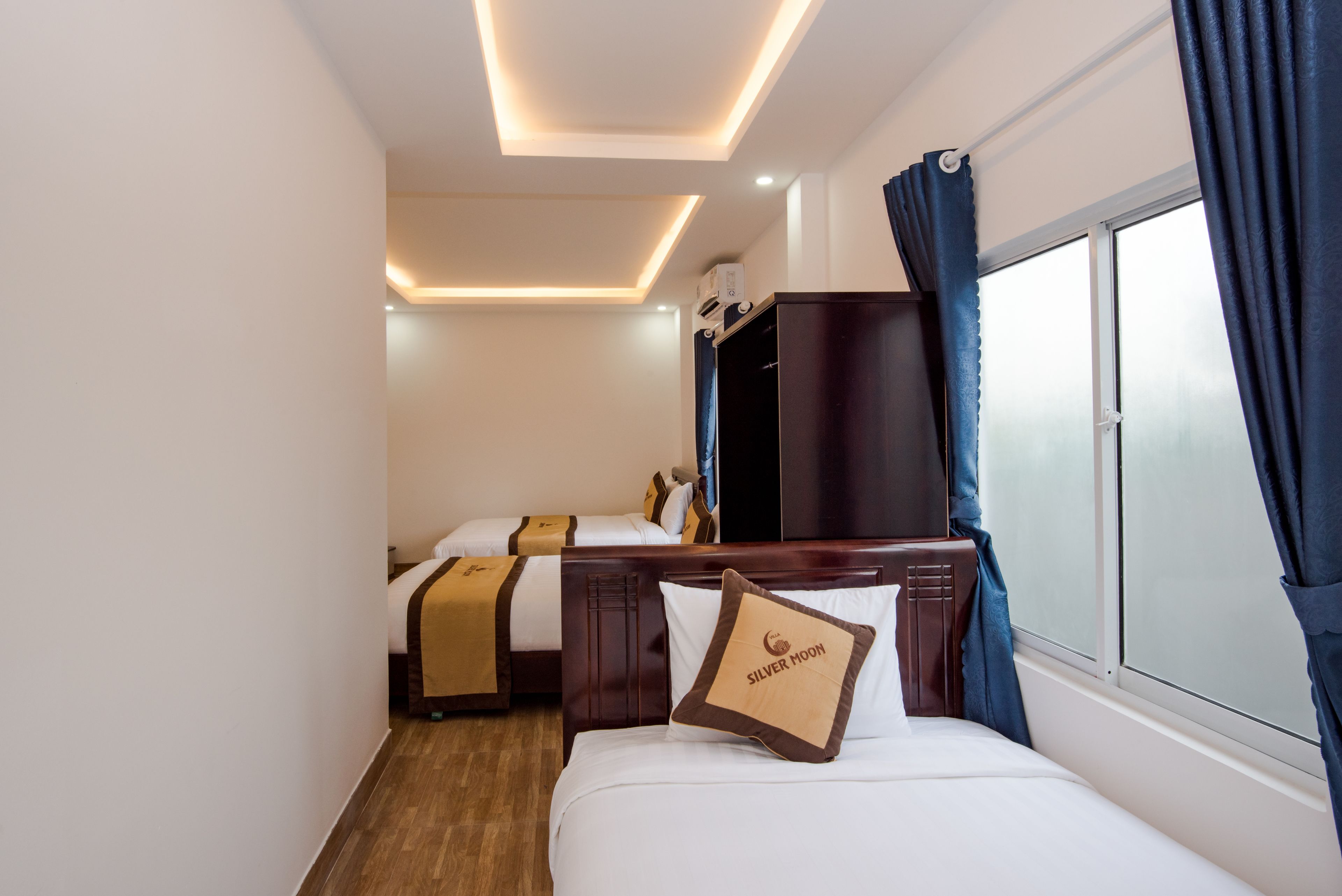 A hotel room with two beds, a wardrobe, and a window with curtains.