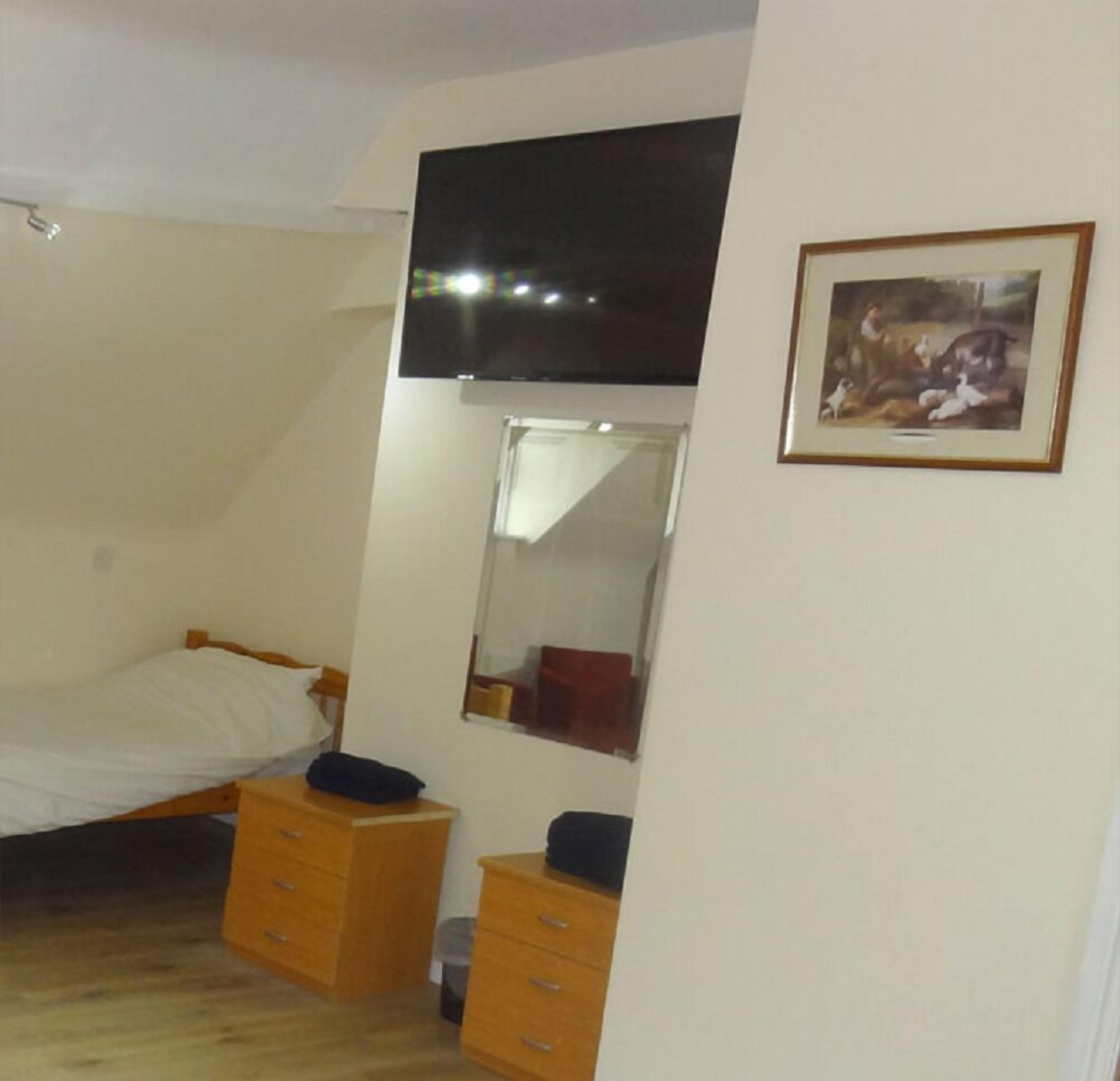 Une pièce comprenant un lit, une commode, un miroir et un tableau encadré accroché au mur.
