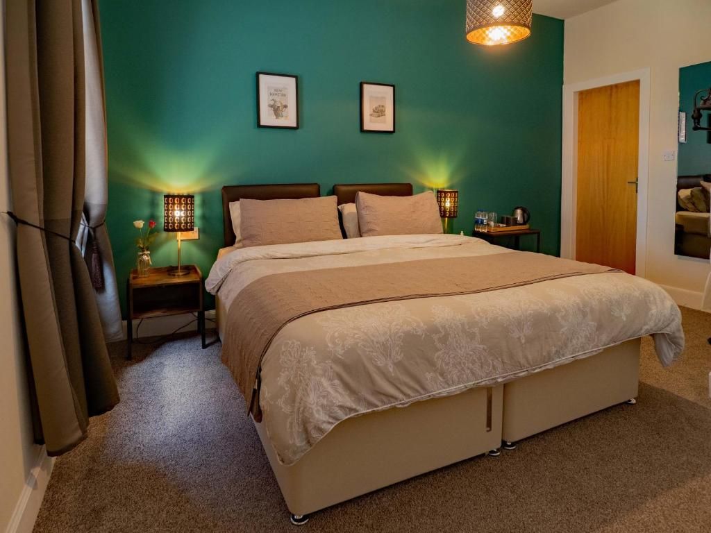 A bedroom with a bed, two bedside tables, a nightstand, a lamp, and a door.