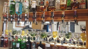 Zona de bar con diferentes botellas de licores y vasos.