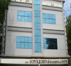 Hotel Gopikrishna features a symmetrical facade with a central vertical element and rectangular windows.