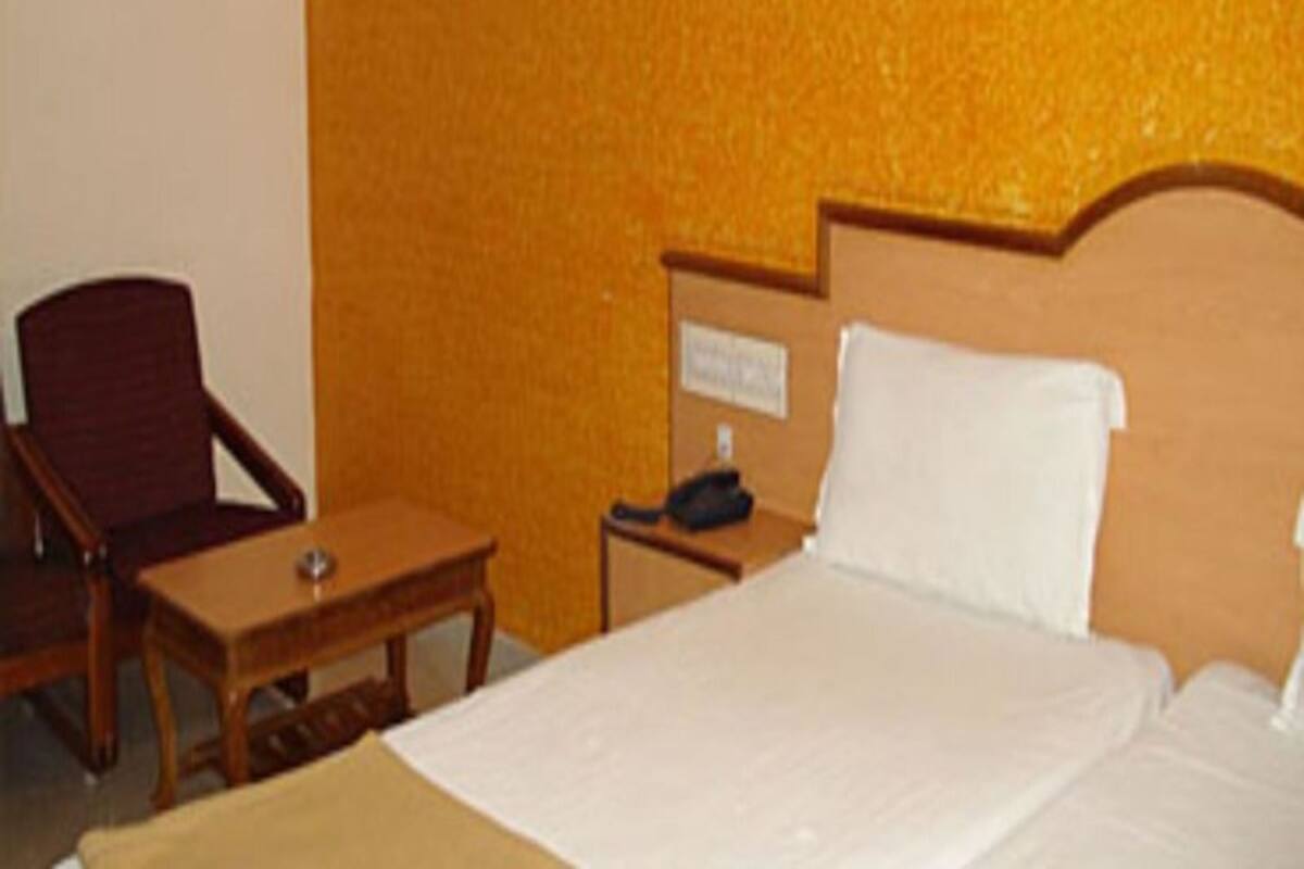 Una habitación de hotel con una cama, una mesita de noche de madera, una silla y una pequeña mesa.
