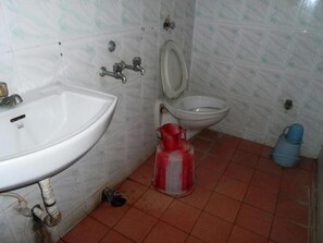 A bathroom with a sink, toilet, and a red gas cylinder. - Hotel Gopikrishna (Tirupati)