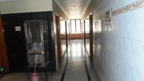 A corridor with a black and white tiled floor, a glass partition on the left, and a wooden door at the end.