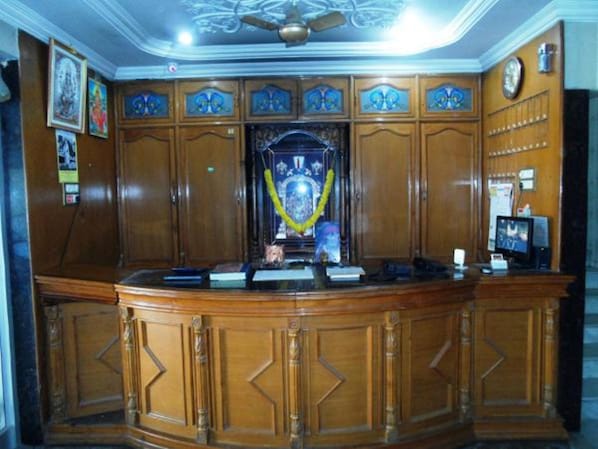 Reception area features a carved wooden desk, framed artwork, and a mounted television.