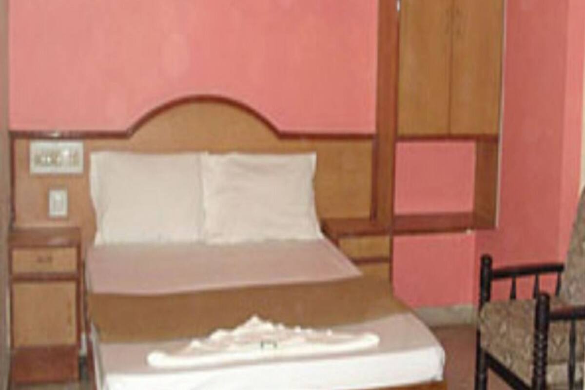 Un dormitorio con una cama de madera, una mesita de noche, un armario y una silla.