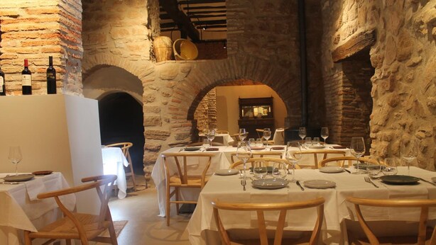 A restaurant with stone walls, wooden tables, and chairs. - Pensión Posada Ignatius (Navarrete)