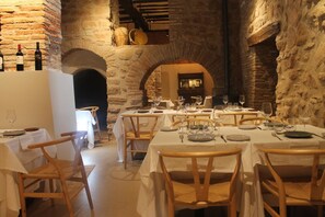 A restaurant with stone walls, wooden tables, and chairs. - Pensión Posada Ignatius (Navarrete)