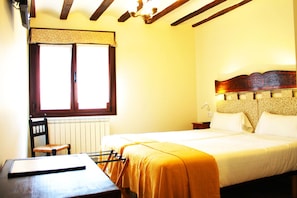 A room with a bed, a chair, a table, and a window.