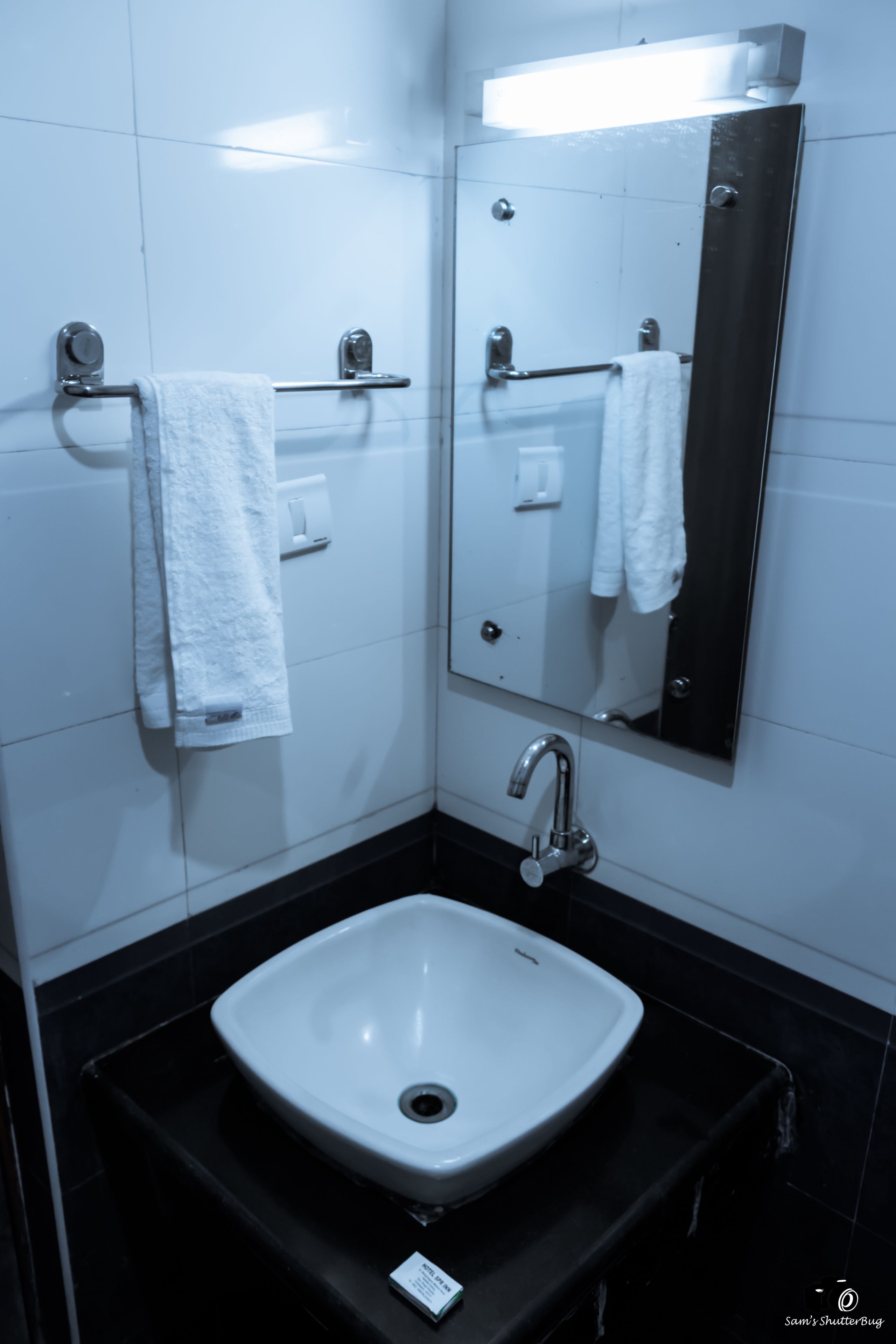 Un baño con un lavabo blanco, un espejo y un perchero para toallas.