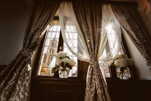 Una ventana con cortinas estampadas y un florero con flores.