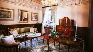 A room with a wooden sofa, a dining table, a chandelier, and a mirror. - Heritage Hotel Cardo (Split)