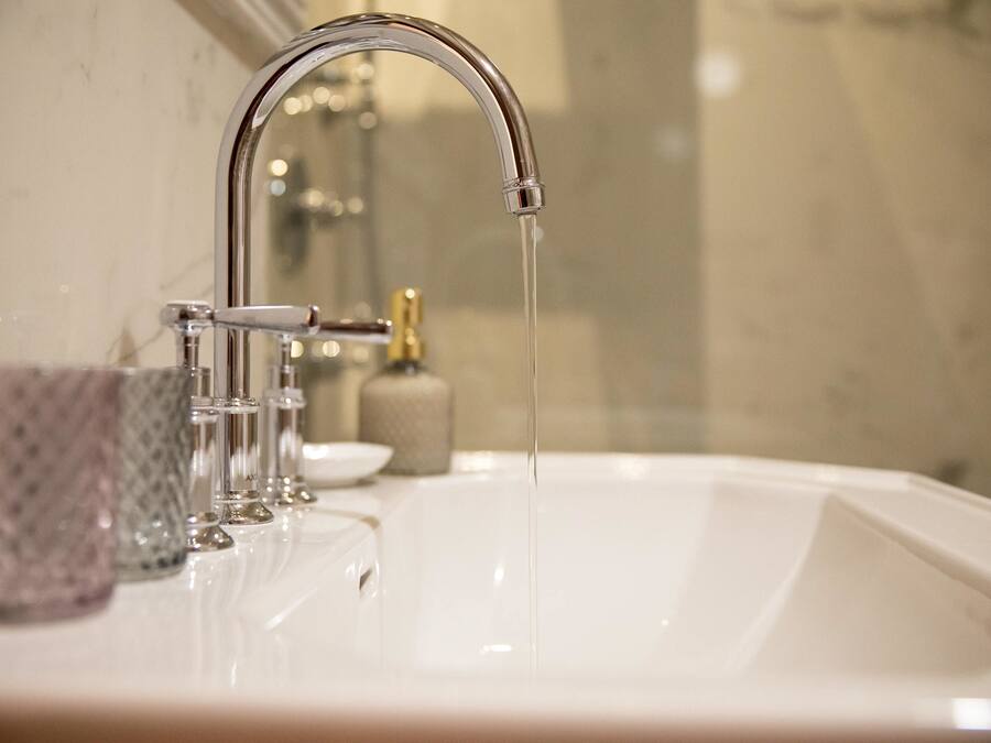 A bathroom sink with a chrome faucet and running water.