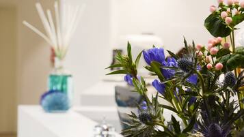Un mostrador de recepción con un florero, un dispensador de gel hidroalcohólico y un pequeño objeto decorativo.