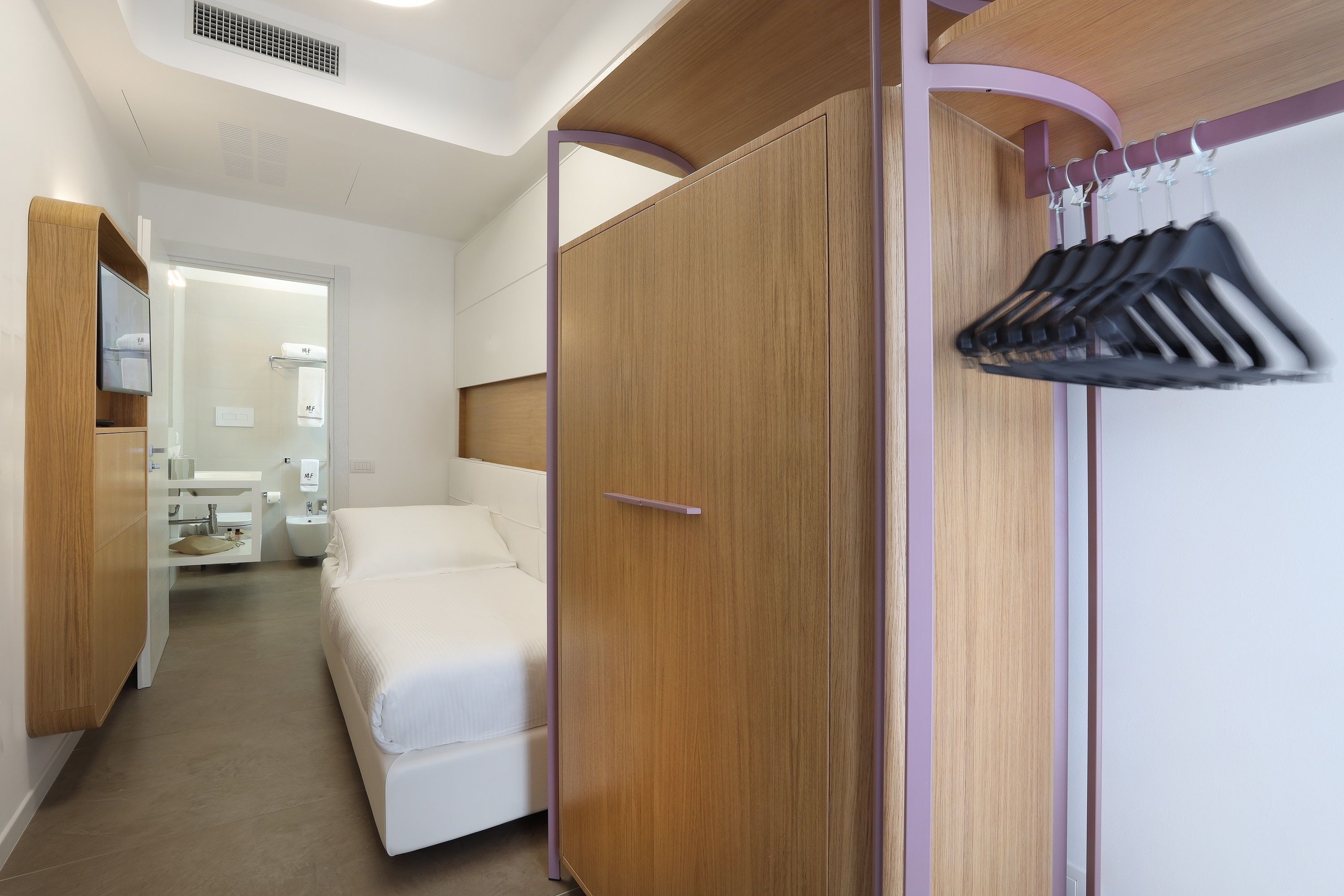 A bedroom with a bed, wardrobe, and a mirror.