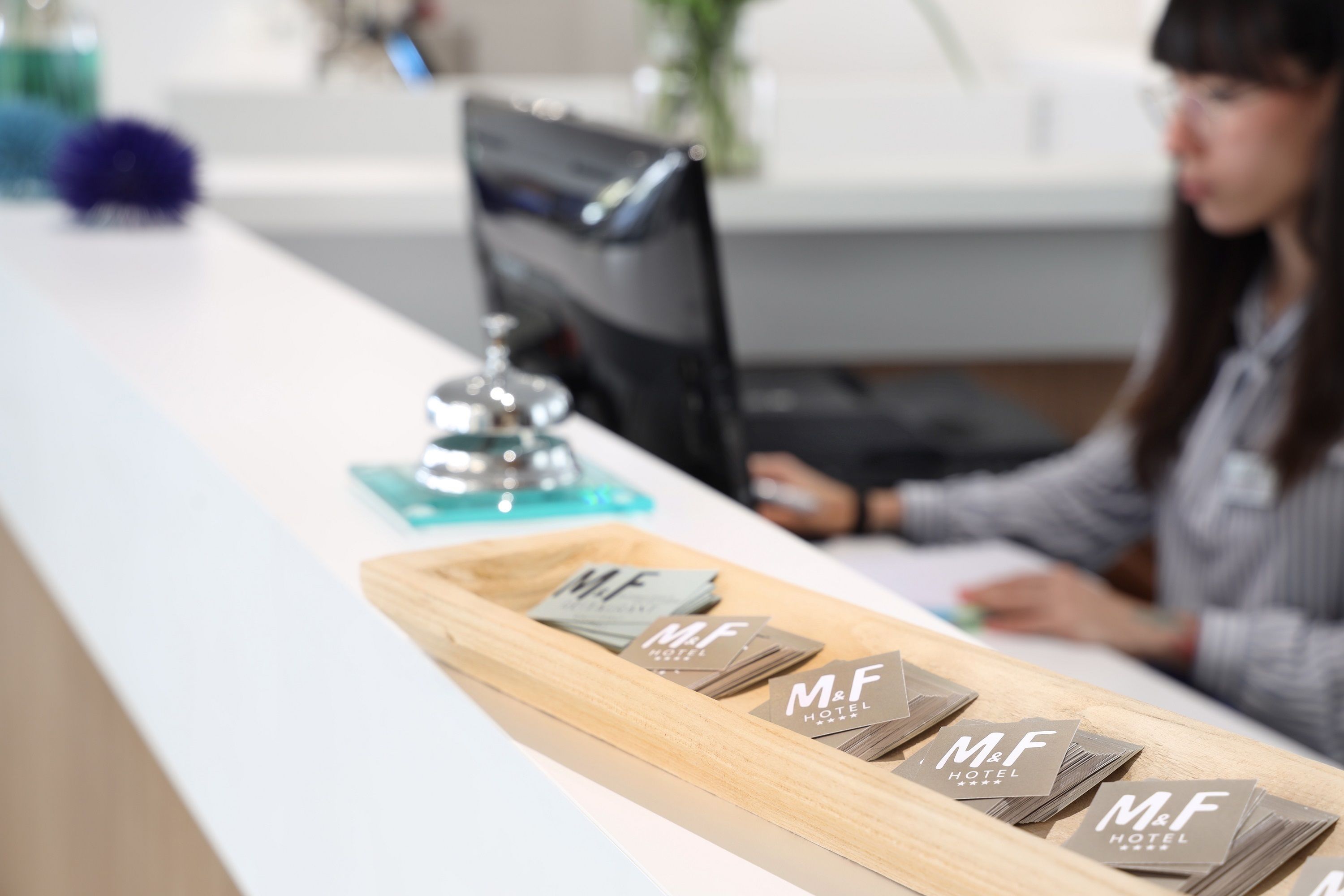 Un comptoir d’accueil avec un présentoir contenant des cartes de visite de l’hôtel M&F.