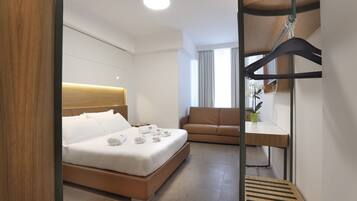 Una habitación de hotel moderna con cama, sofá, escritorio y una silla colgante.