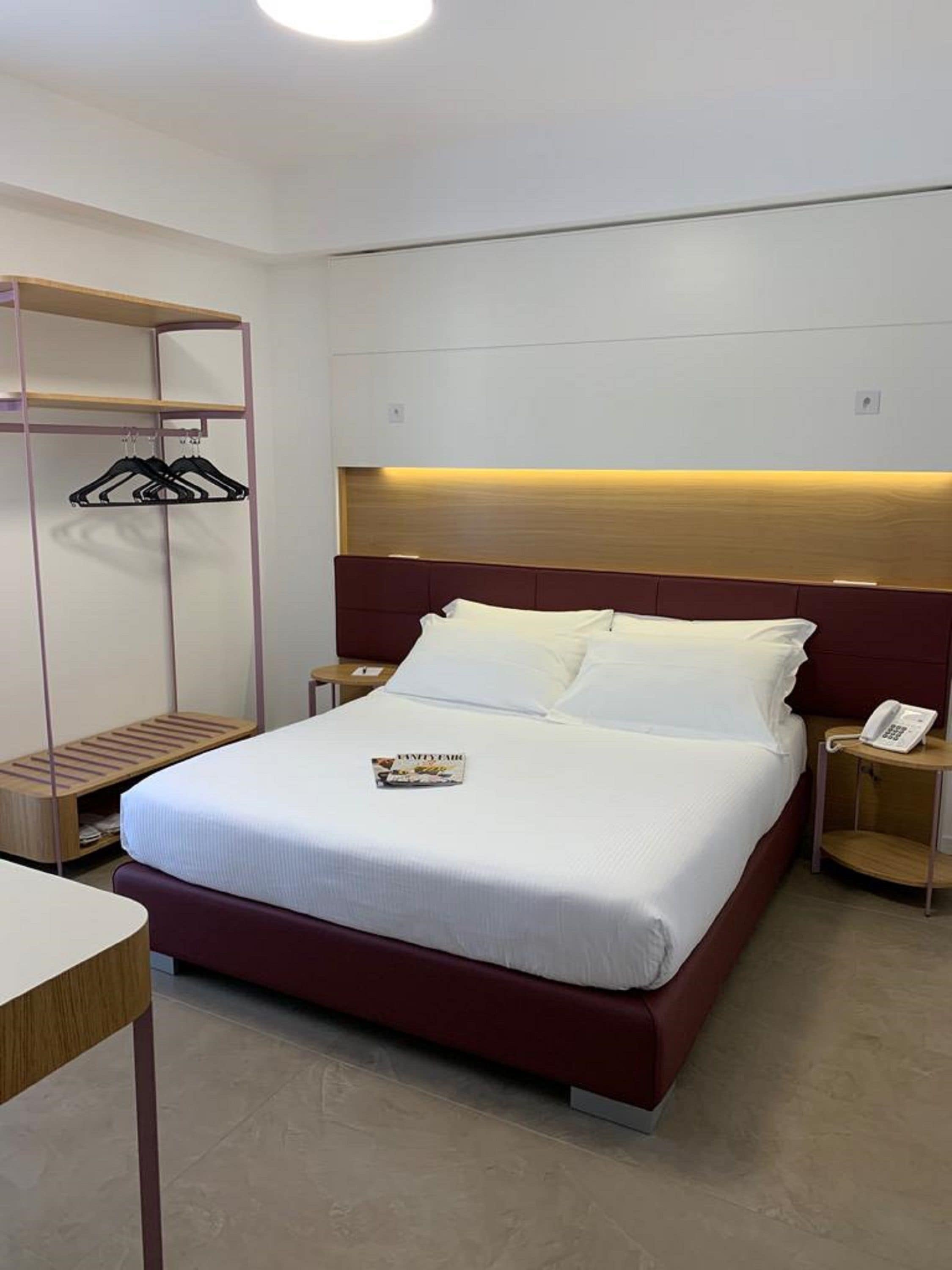 Quarto de hotel bem organizado, com cama, mesas de cabeceira, guarda-roupa e uma revista sobre a cama.