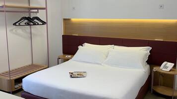 Quarto de hotel bem organizado, com cama, mesas de cabeceira, guarda-roupa e uma revista sobre a cama.