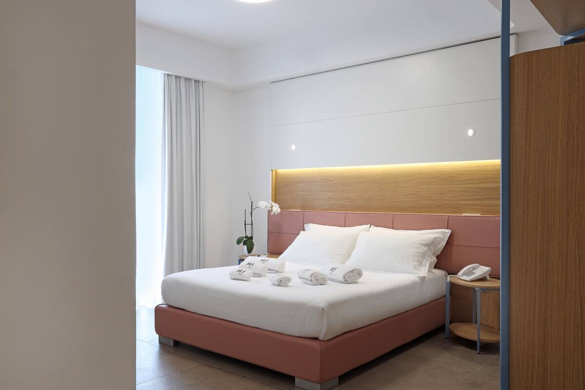 Una habitación de hotel moderna con una cama, una mesita de noche con un teléfono y una lámpara.