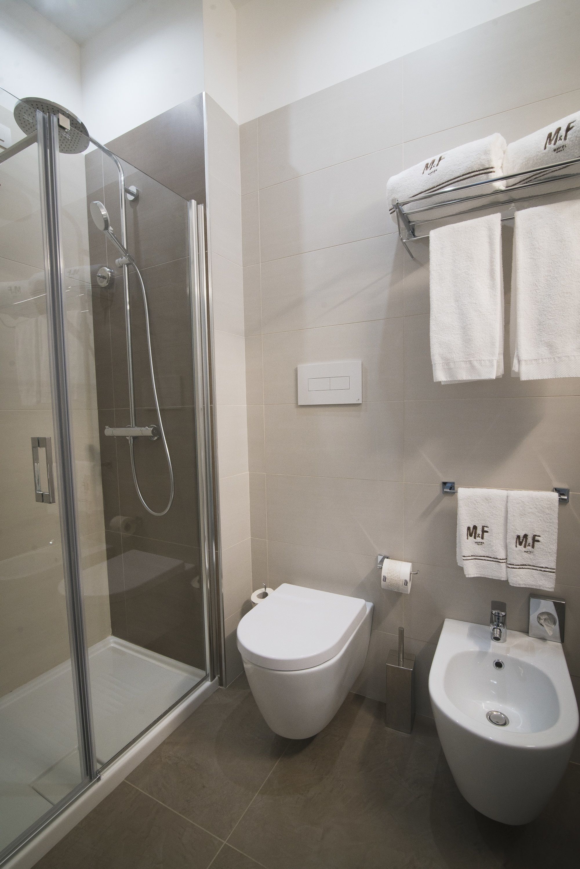 Un baño moderno con ducha de vidrio, inodoro y bidé.