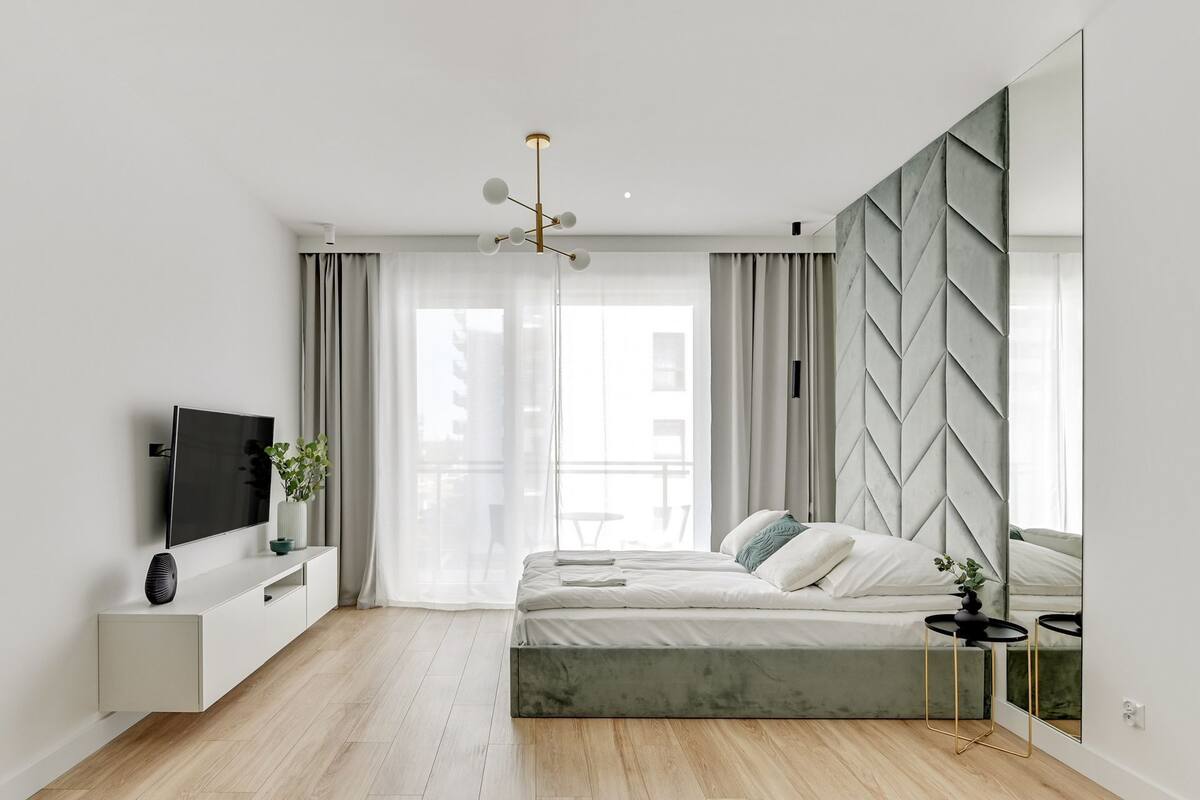 Une chambre à coucher moderne avec un lit, une télévision et un miroir.